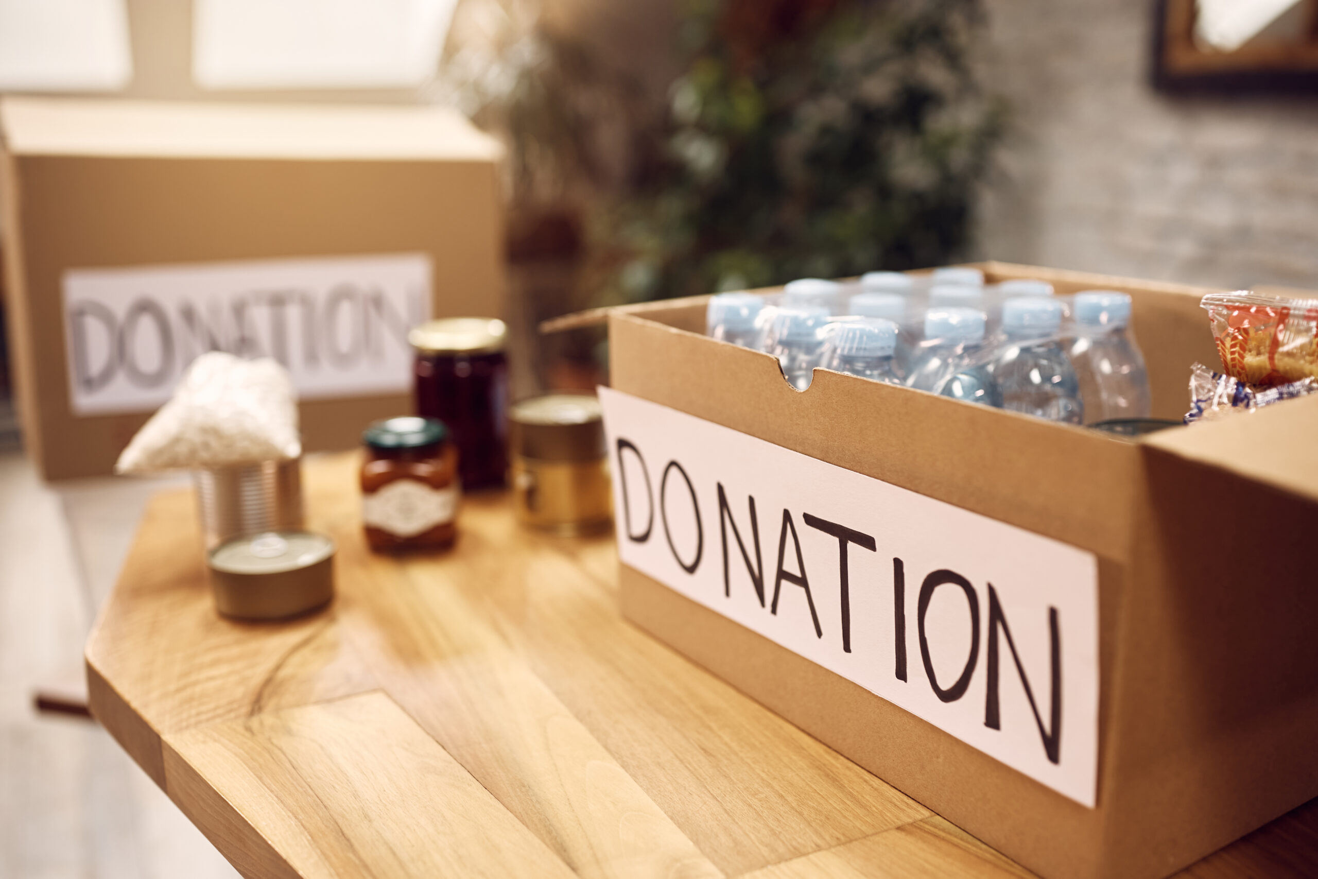 Close-up of donation box with bottled water and canned food. Copy space.